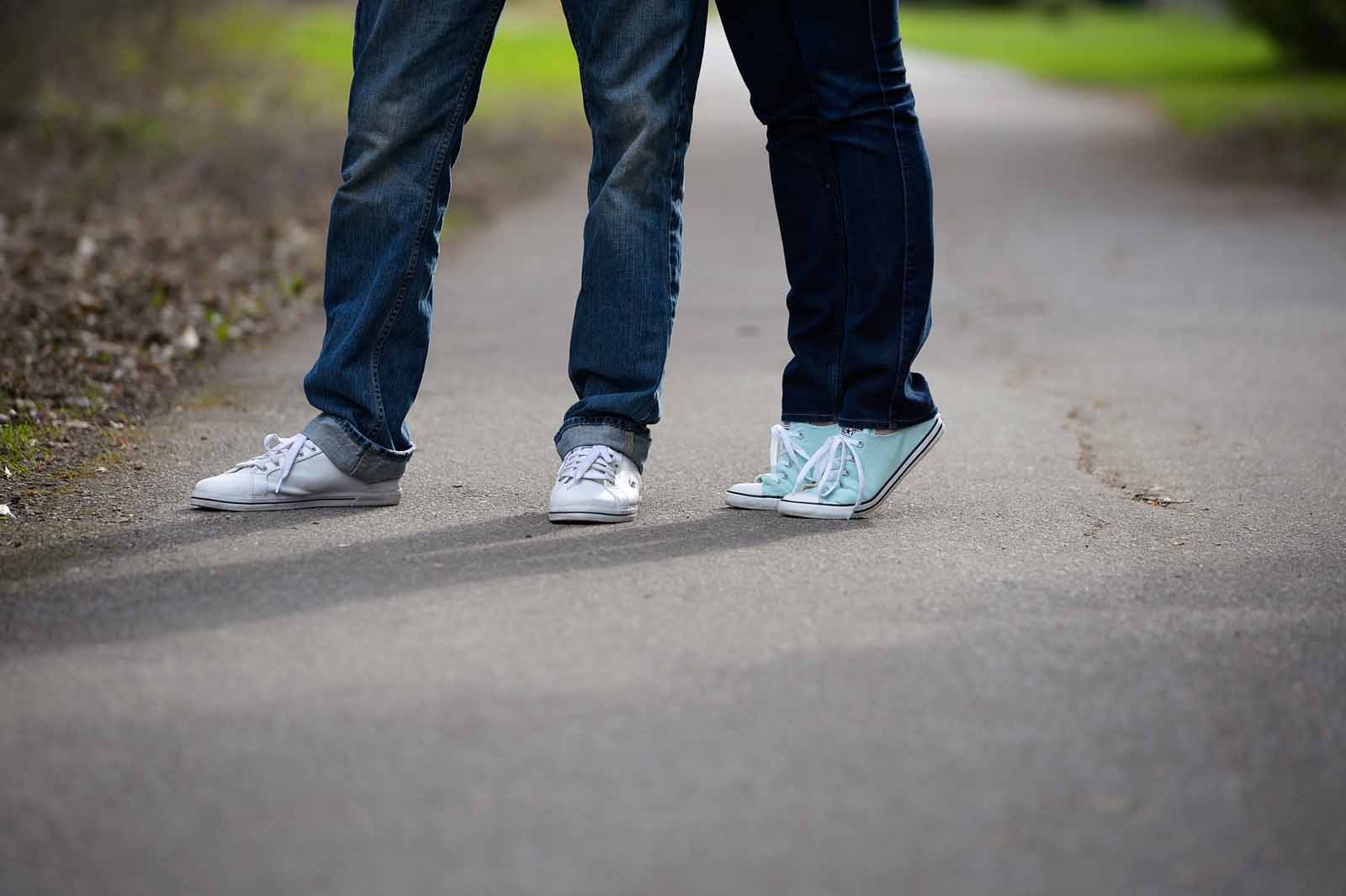 A couple’s shoes where one is on tip toe to reach the other for an unseen kiss on a pathway in Ottawa