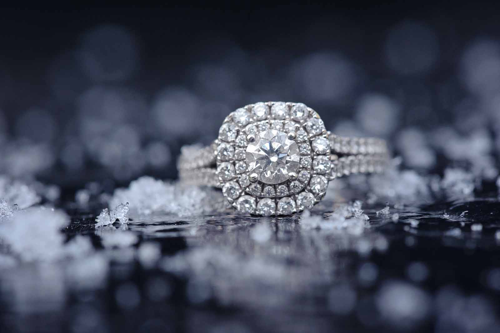 An engagement ring sitting on a shiny surface with snow all around it in Ottawa