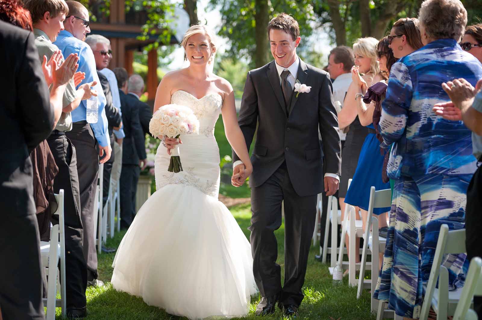 Bride and groom leaving their ceremony after being declared husband and wife on a sunny summer day at The Marshes Golf Club where they had their wedding