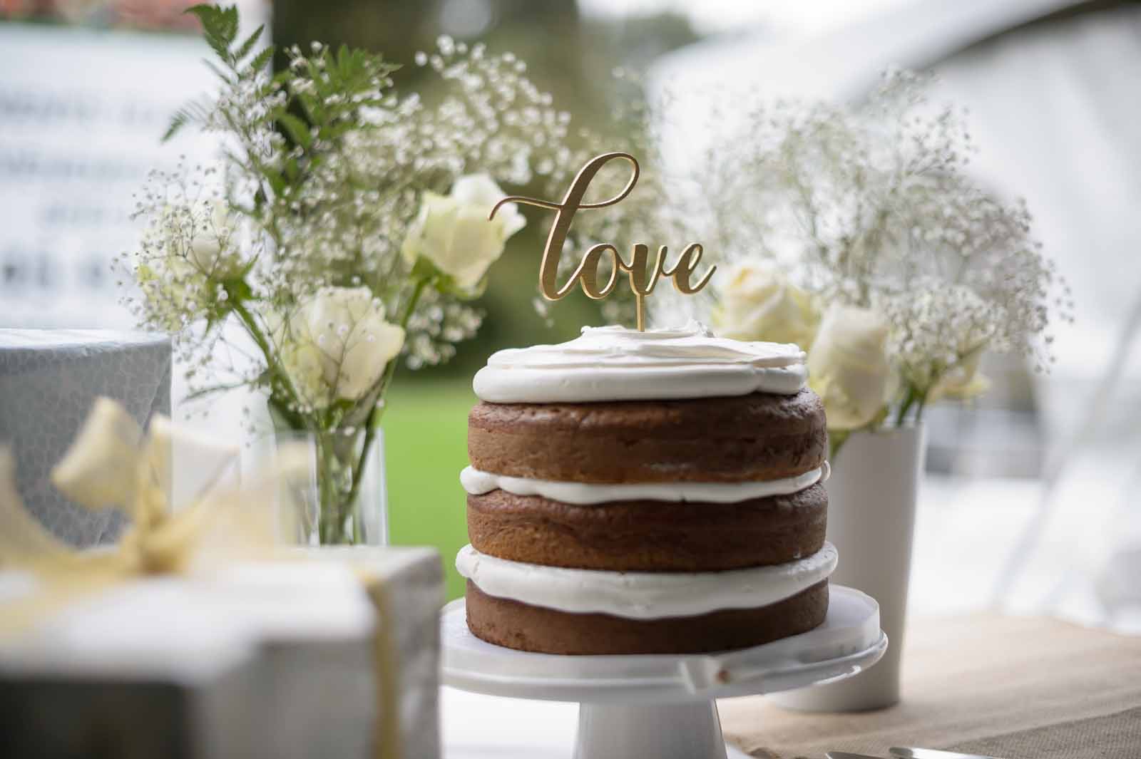 Wedding cake with a love cake topper surrounded by flowers