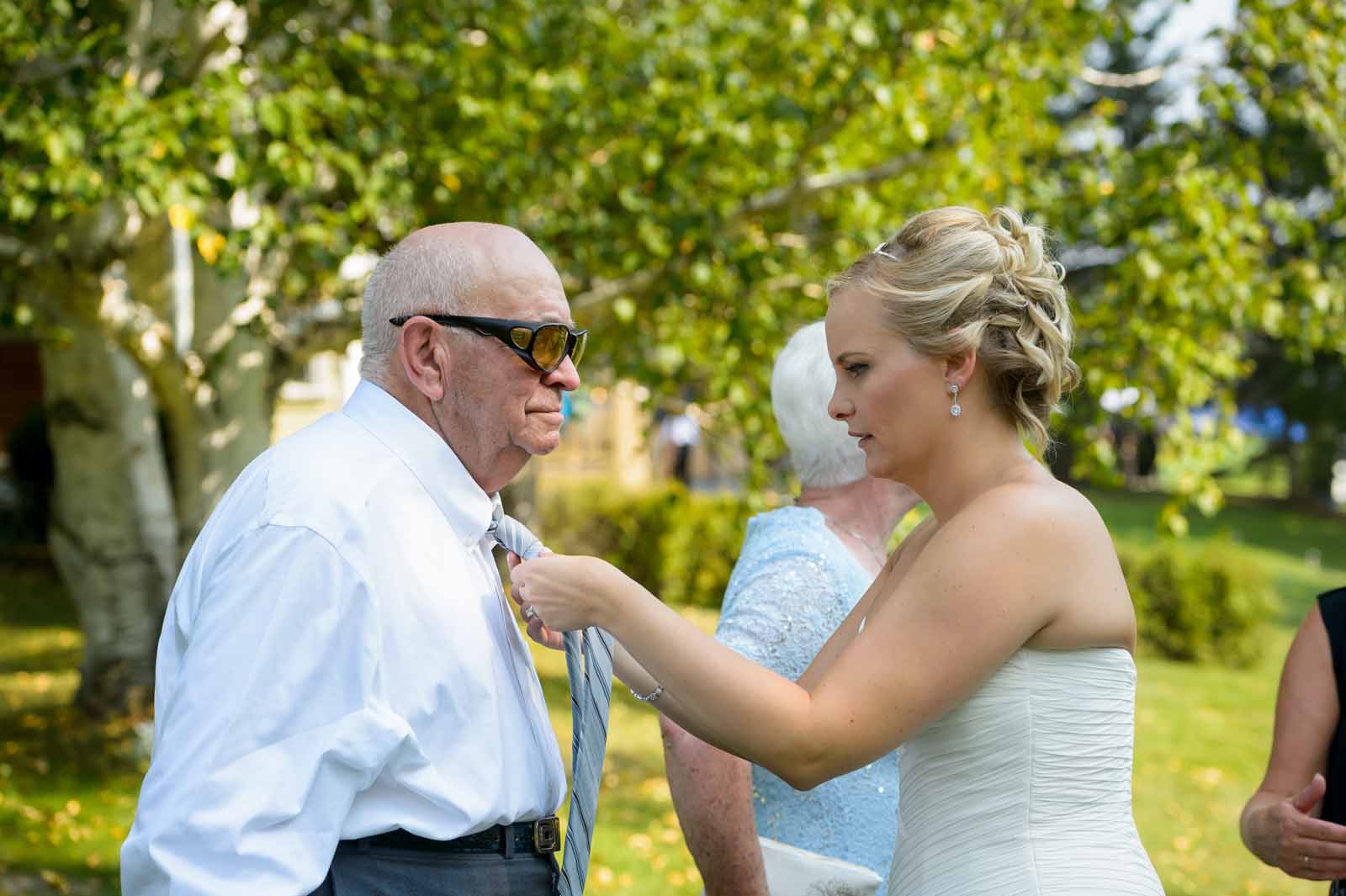 Bride fixing her grandfather tie on her wedding day