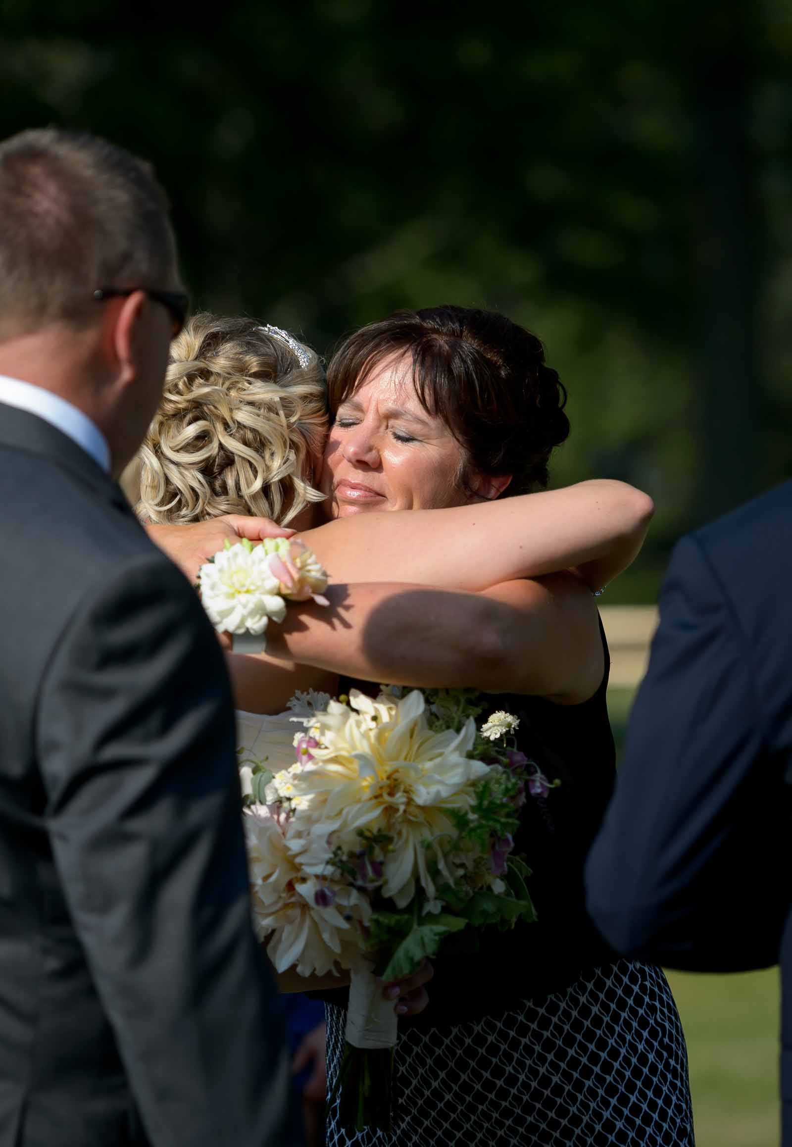 Mother of the bride hugging the bride on her wedding day in congratultions