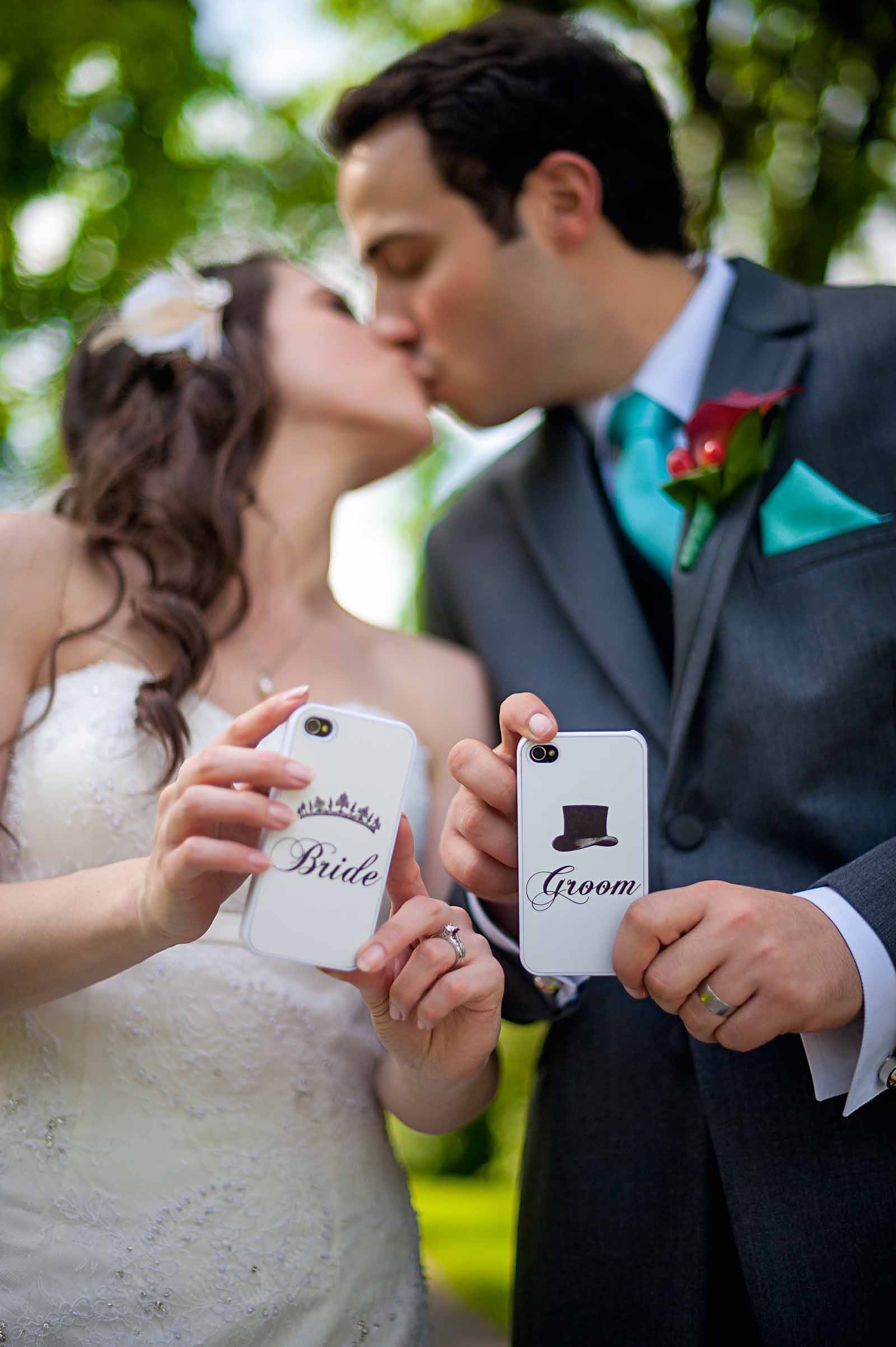 Kissing couple showing their new iPhone cases stating Bride and Groom