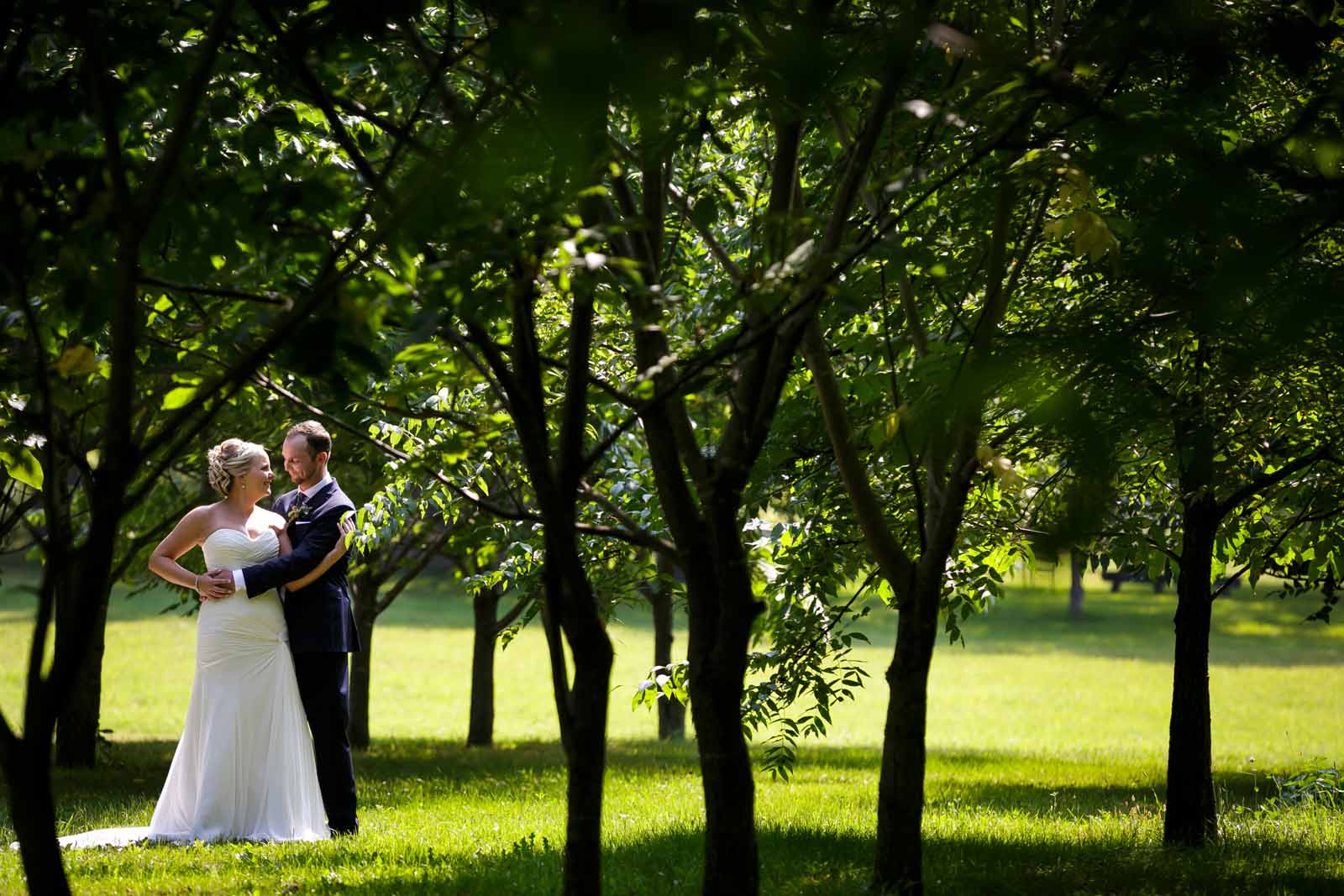 Couple embracing amongst the trees on their wedding day