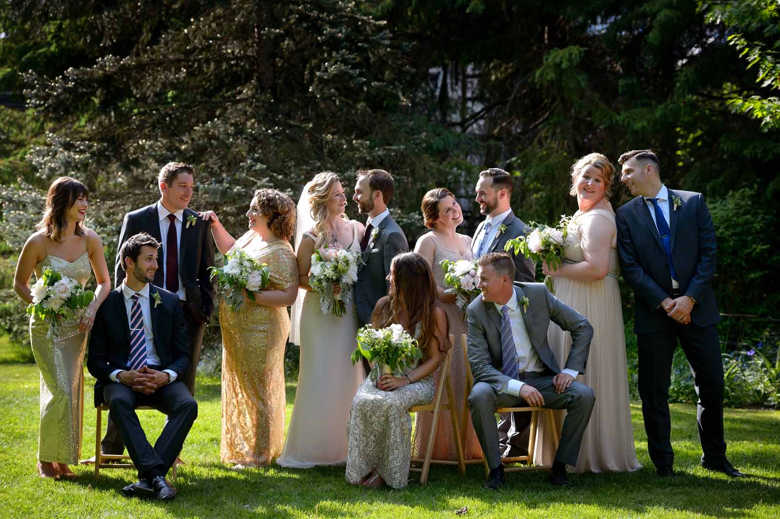 Big wedding party all looking at each other and laughing on a warm May day at Saunders Farm in Ottawa