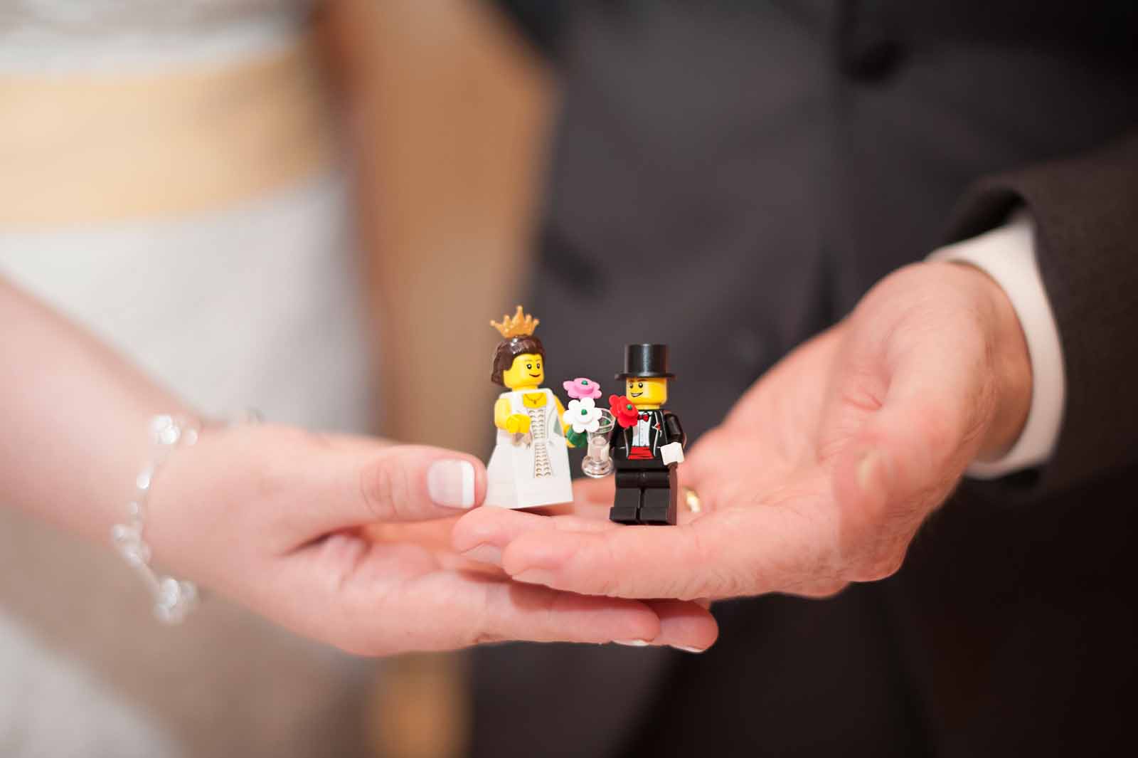 Bride and groom holding wedding themed lego mini figs at their reception
